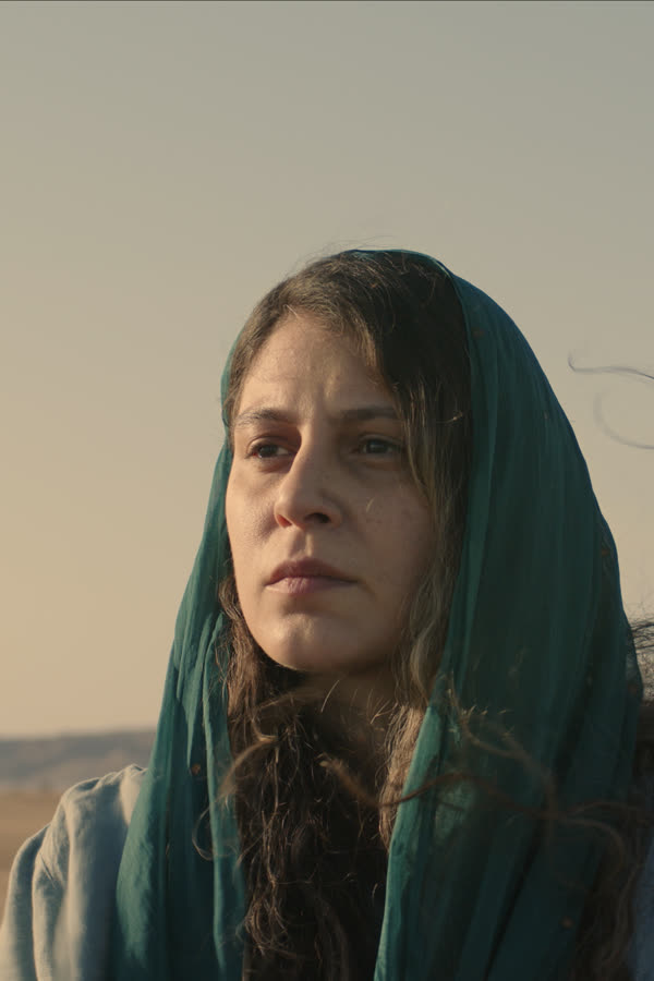 Still from From The Sea: a woman in a green headscarf on a windswept beach