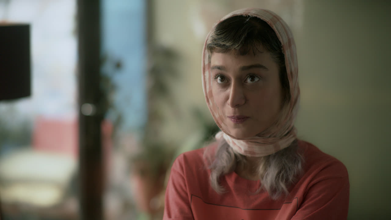 A young woman in a headscarf looks across a room