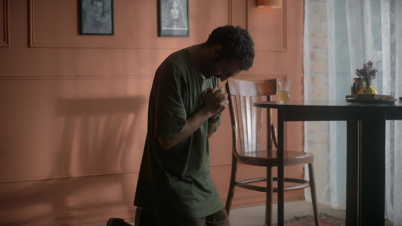 A man kneels on the floor of a terracotta-coloured room