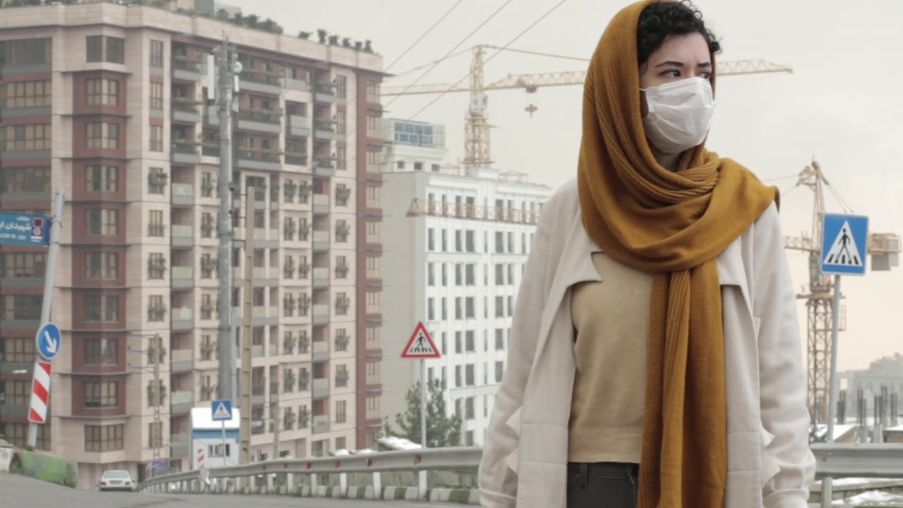 A young woman in a face mask by a building site