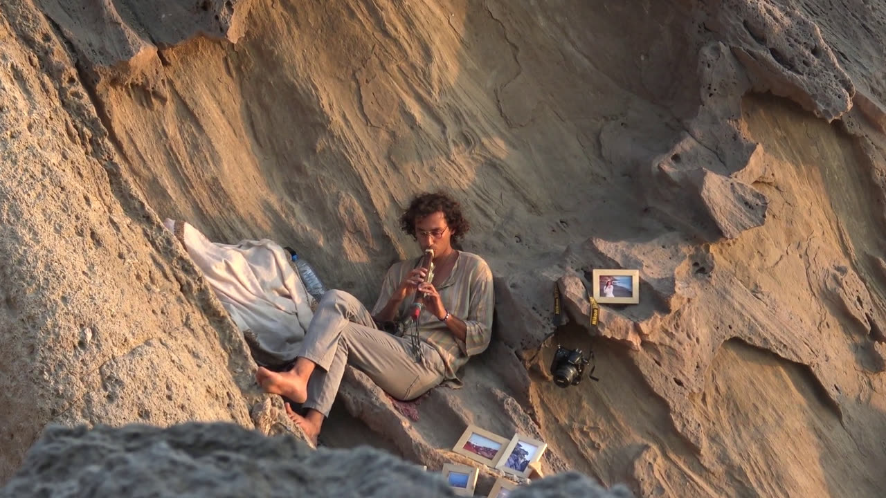 A young woman sits in a hollow of sandstone rocks